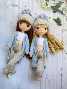 two knitted dolls sitting next to each other on top of a white wooden surface