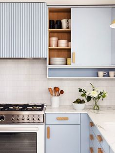 a kitchen with blue cabinets, white counter tops and wooden utensils on the stove