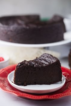 a piece of chocolate cake on a red and white plate next to a bundt cake