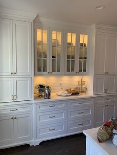 a kitchen with white cabinets and wood floors