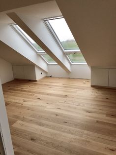 an empty room with wooden floors and skylights in the roof window sill area