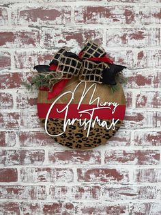 a christmas ornament hanging on the side of a brick wall with a leopard print bow