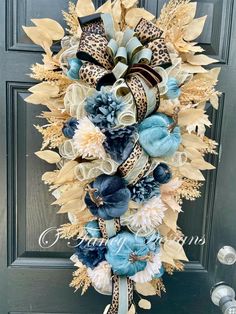 a wreath with blue flowers and leopard print ribbon hanging on the front door's side