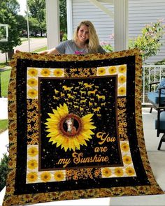 a woman holding up a sunflower quilt with the words you are my sunshine on it