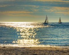 a sailboat in the distance on an ocean beach