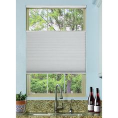 a kitchen window covered in blinds with bottles on the counter and wine bottles next to it