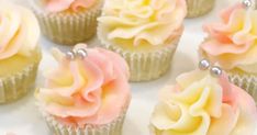 cupcakes with pink and yellow frosting on white paper, decorated with pearls