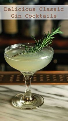 a gin cocktail in a coupe glass with a sprig of rosemary garnish