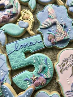 decorated cookies with mermaids and sea creatures are displayed on a table in front of the number five