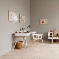 a white desk and chair in a room with wood flooring next to a bed