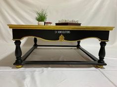 a black and gold coffee table with chess pieces on it's top, in front of a white backdrop