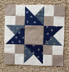 a blue and gray star quilted on the floor next to a brown wall hanging