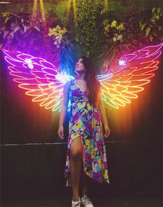 a woman standing in front of a wall with angel wings on it