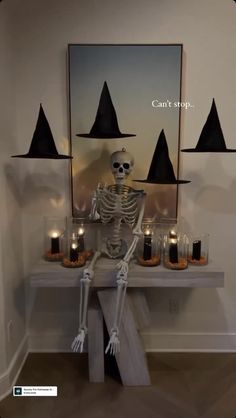 a skeleton sitting on top of a table with candles