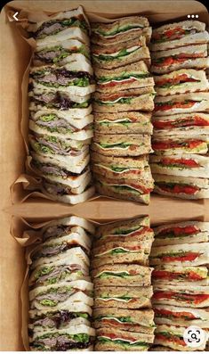 there are many different sandwiches in the box on the table and one is stacked high