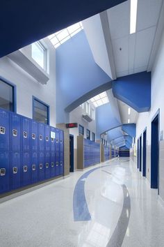 an empty school hallway with blue lockers and white flooring on the side wall