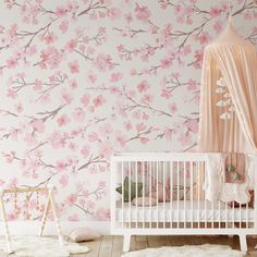 a baby's room with pink flowers on the wall and a crib next to it