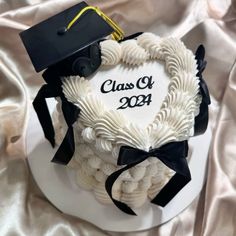 a graduation cake is decorated with white icing and black ribbon