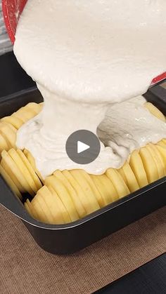 an image of food being prepared in a pan on the table with white sauce pouring over it