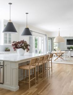 a large kitchen with an island and two pendant lights over the stove top, surrounded by chairs