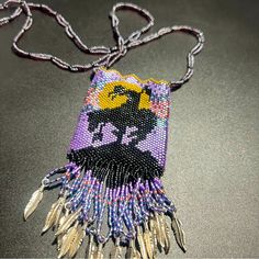 a beaded necklace with an image of a woman on it and feathers hanging from the front