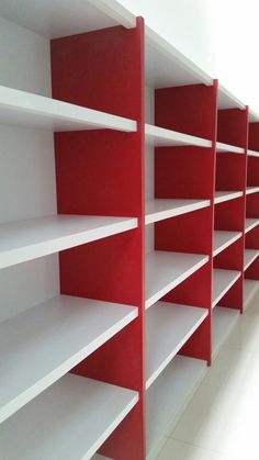 empty red and white shelving in a room with tile flooring, two rows of shelves on each side