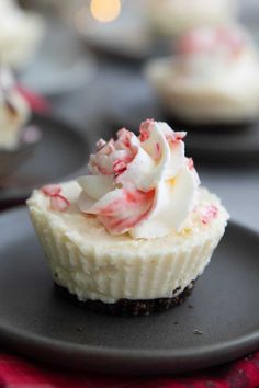 a cupcake with white frosting and candy canes on top is sitting on a black plate