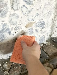 a person is using a sponge to clean the stone wall with an orange cloth on it