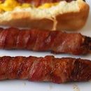 two bacon wrapped hotdogs sitting next to each other