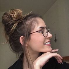 a young woman with glasses is smiling and looking at the insect on her wall behind her