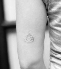 a woman's arm with a small cup tattoo on the left side of her arm