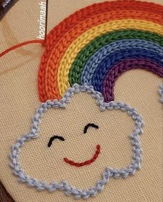 a close up of a cross stitch pattern with a rainbow in the middle and a smiling face on it