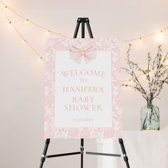 a welcome sign for a baby shower is displayed on a easel with lights in the background