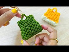 a hand holding a crocheted purse keychain next to a small bag