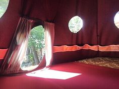 the inside of a tent with three round windows and red carpeted flooring in front of it