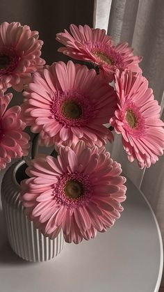 some pink flowers are in a white vase