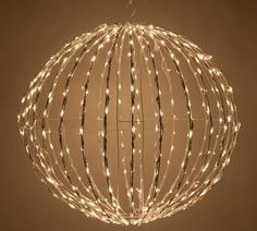 a lighted ball hanging from the ceiling with branches and lights on it's sides