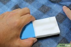 a person is holding a small device in their hand on a blue and gray blanket