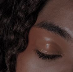 a close up of a person's eye with long hair and brown eyeshadow