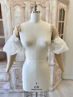 a white mannequin with ruffles on it's arms and shoulders