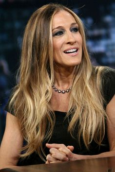 a woman sitting at a table in front of a microphone and wearing a black dress