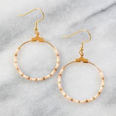 Your soon-to-be favorites, these small gold beaded hoops (available in 22 exclusive patterns) are perfect for day, night and well, everything in between. gold-plated hoop and hooks lead-free and nickel-free glass seed beads plastic earring back 1.25" in diameter and overall length is 2" from top of hook packaged on a hand-stamped kraft earring card in a clear resealing bag EXCLUSIVE STYLES NAVY Navy blue, bronze, and blush PHOENIX Turquoise, red, cream, and gold GREY Matte black, metallic pink, Nickel Free Summer Hoop Earrings, Nickel-free Circle Hoop Earrings For Summer, Summer Nickel Free Hoop Earrings, Summer Nickel-free Hoop Earrings, Adjustable Hoop Earrings With Gold Beads As Gift, Adjustable Gold Beads Hoop Earrings As Gift, Adjustable Gold Beaded Hoop Earrings As Gift, Nickel-free Heishi Bead Hoop Earrings, Nickel-free Hoop Earrings With Heishi Beads