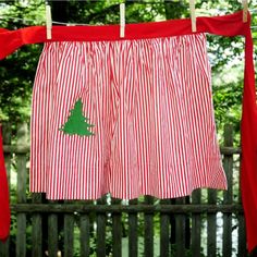 red and white striped curtains hanging from a clothes line with a green christmas tree on them