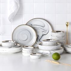 white marble dinnerware set with gold rims and spoons on a countertop