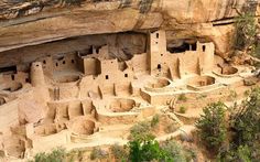 the cliff houses are built into the side of the mountain, with people standing near them