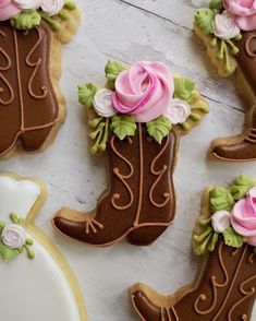 decorated cookies in the shape of cowboy boots and flowers on top of a white table