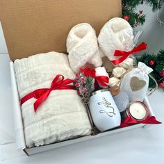 a box filled with towels, candles and other holiday items next to a christmas tree