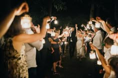 a group of people standing around each other holding lit up candles in the air at night