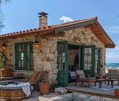 an outdoor hot tub sitting next to a stone building with green doors and shutters