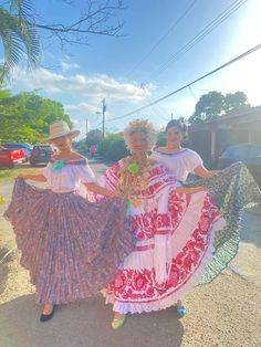 two women in colorful dresses are dancing on the street